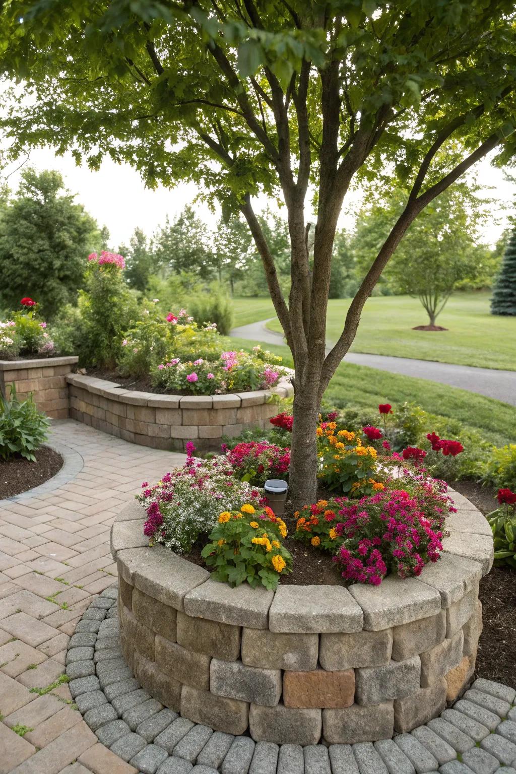 A tree nestled within a raised paver planter, blooming with flowers.