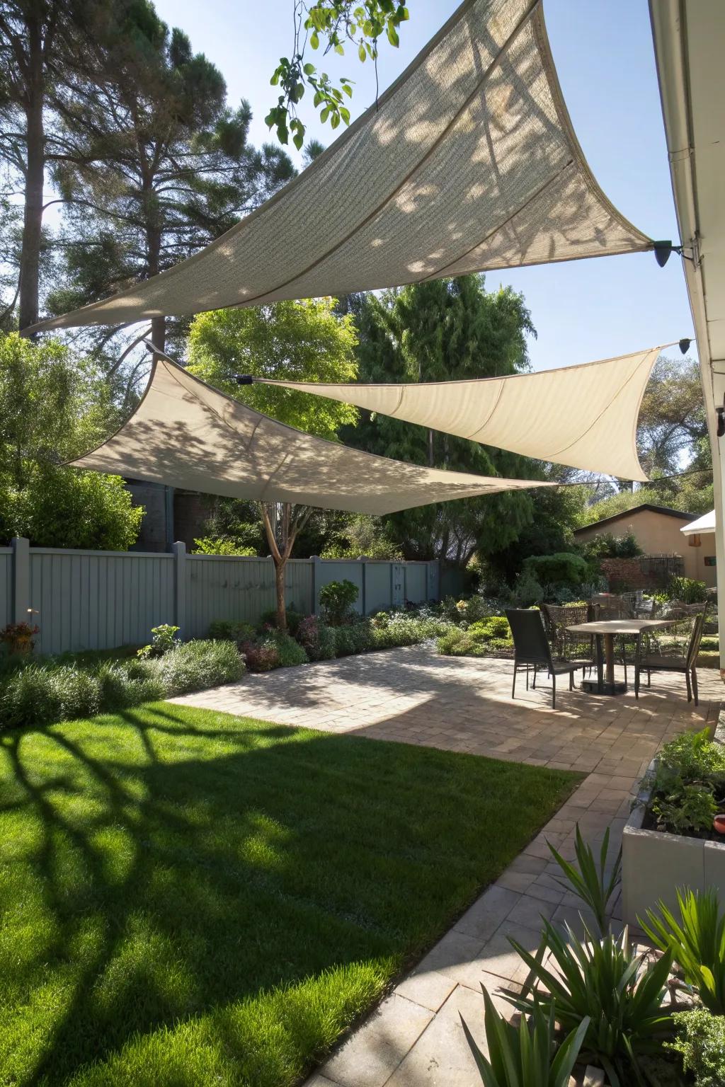 Multi-level sail shades offering dynamic shadow patterns in a backyard.