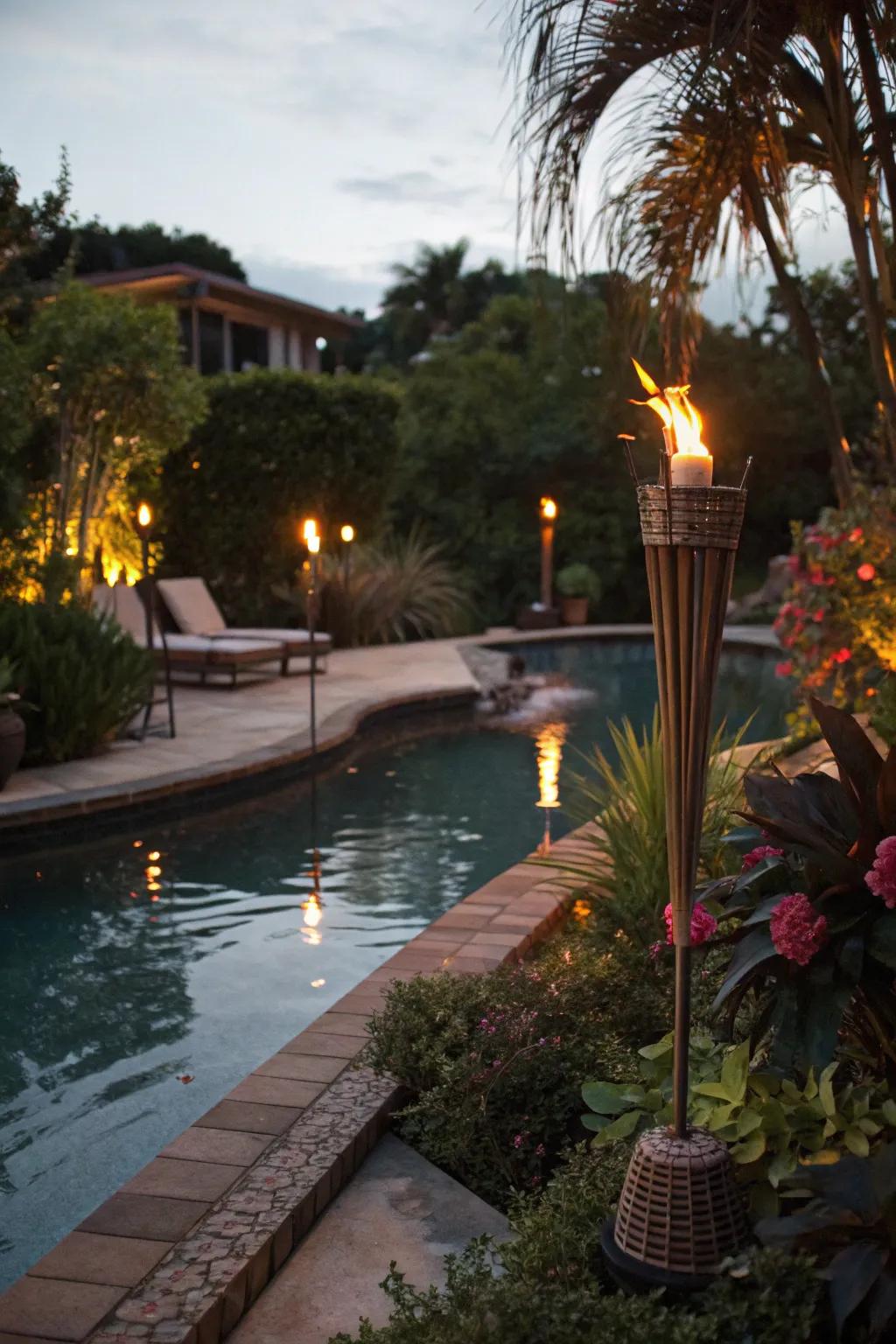 Tiki torches casting a warm glow over a tropical pool setting at dusk.