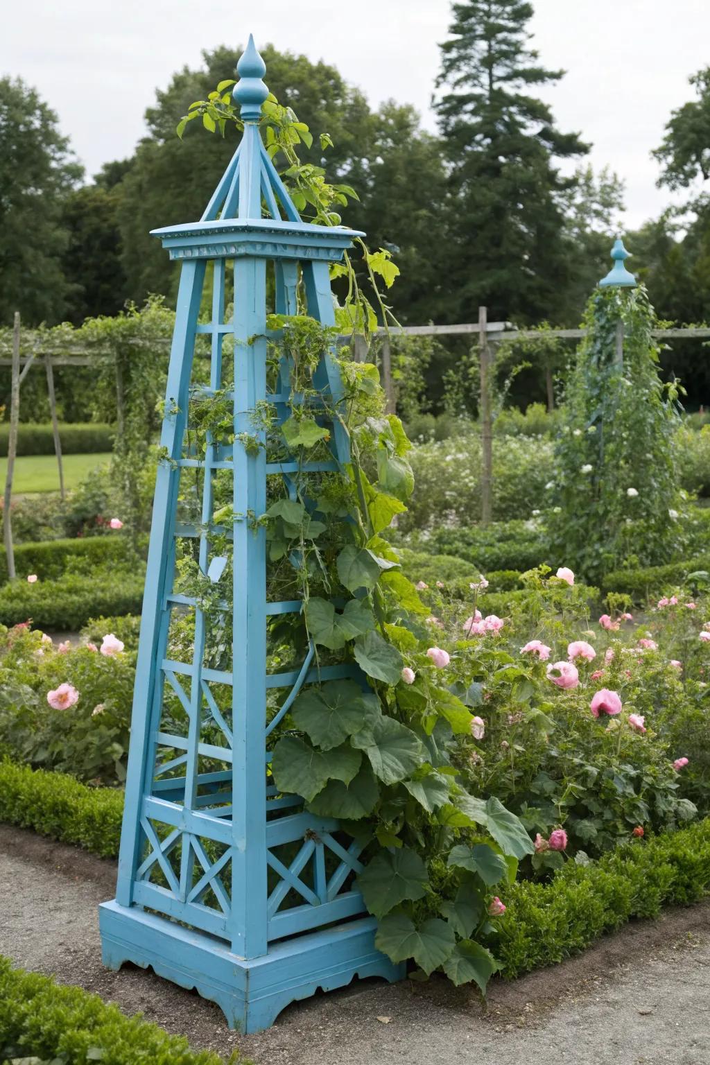 A striking blue obelisk trellis adorned with cucumbers.