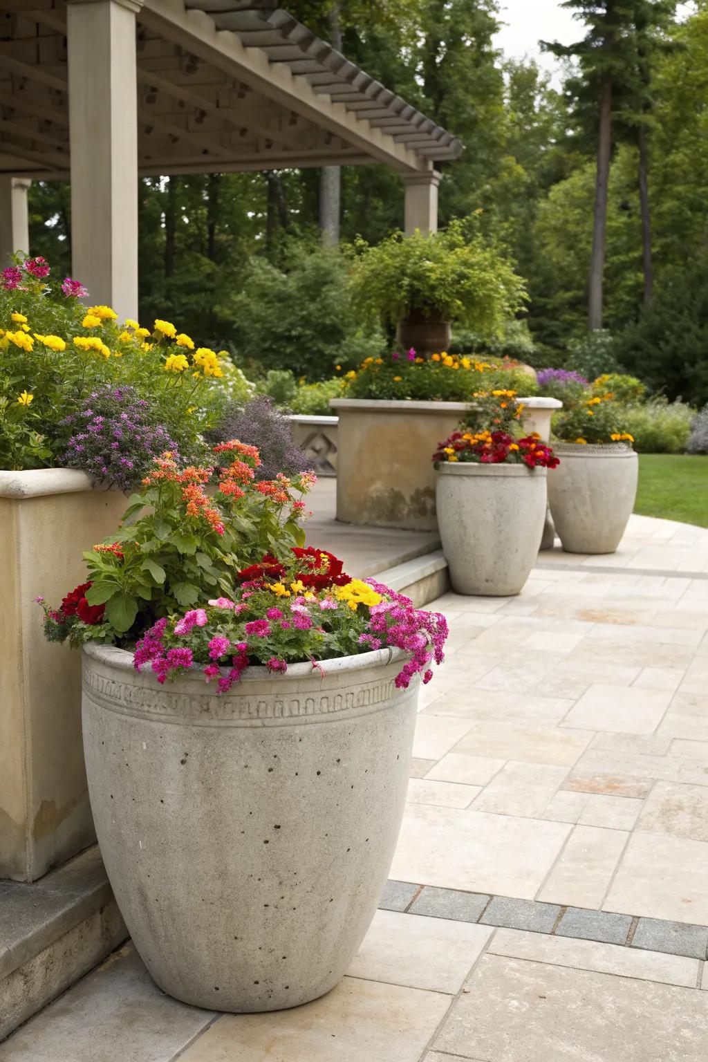 Large concrete planters filled with colorful flowers on a stylish patio.
